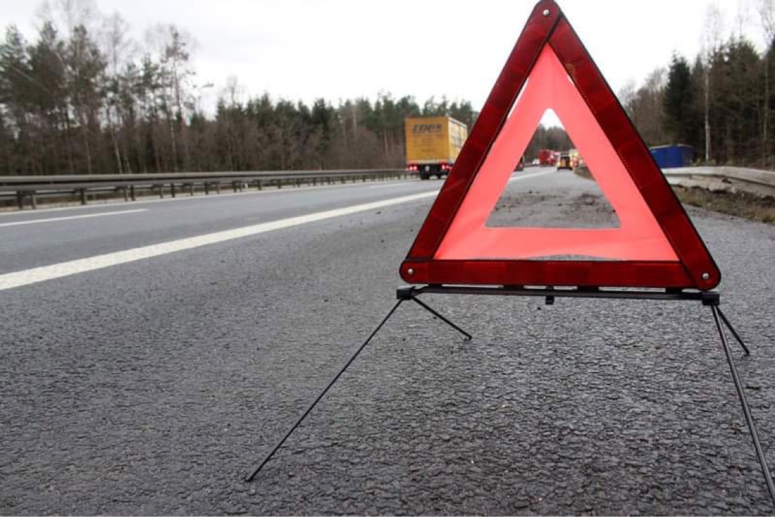 En närbild på en varningstriangel uppställd på en motorväg. Detta är en genrebild.