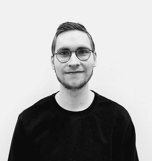 Porträttbild på Leonard. Han ler mot kameran och har en svart tröja på sig. Bakgrunden är vit.