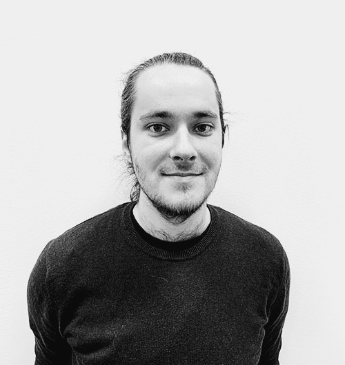 Porträttbild på Joacim. Han ler mot kameran och har en svart tröja på sig. Bakgrunden är vit.