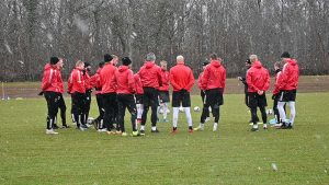 Kalmar FF står samlad i en ring under träningen på förmiddagen. Snöflingor syns falla runt laget i bilden.