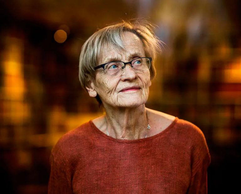 Porträttbild på Karin Nyman. Skärpedjupet är mycket kort och hon tittar bort ifrån kameran. Hon har en röd tröja på sig.