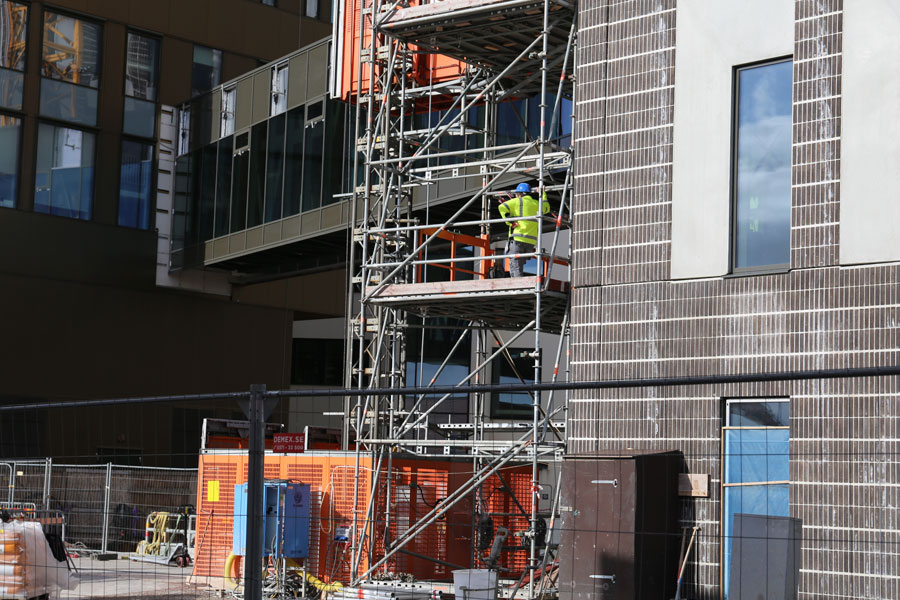 En byggarbetare står och håller i sig i en byggnadsställning.