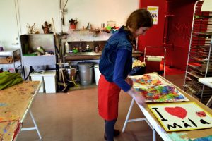 Elisabeth Kettleg Cronfalk tar hand om de målningar som lagts för att torka.