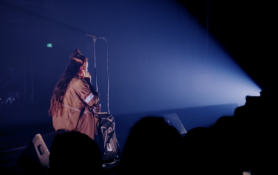 Miriam sitter och lyssnar på när publiken sjunger