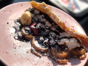 Bild på våffla fylld med bär, glass, grädde och chokladsås.