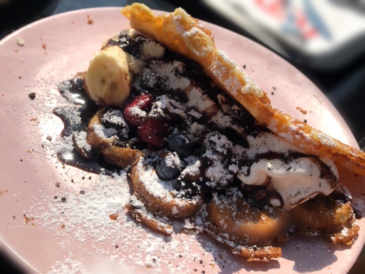 Bild på våffla fylld med bär, glass, grädde och chokladsås.