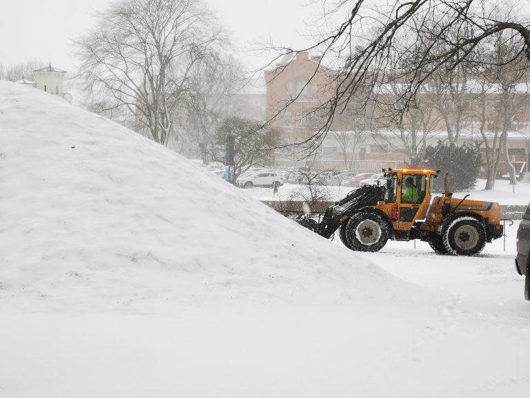 Plogtraktor röjer snö vid en kulle.