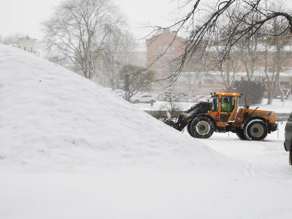 Plogtraktor röjer snö vid en kulle.