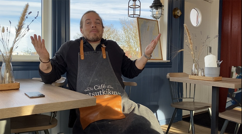 Alfred Nóren sitter i en stol med händerna i luften.