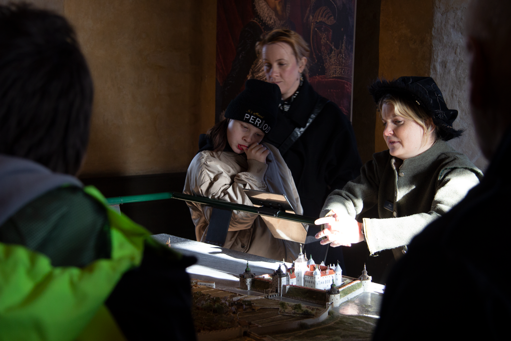 Barn och mamma lyssnar på guiden som pratar om medeltiden