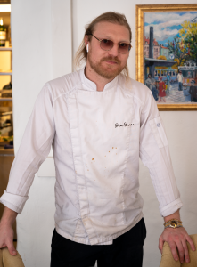 Pontus Lötbom står mellan stolarna i sin restaurang.