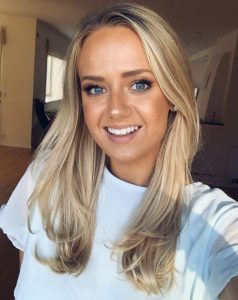 Malin tittar in i kameran och ler. Hon har blondt hår och ljusblå tröja.