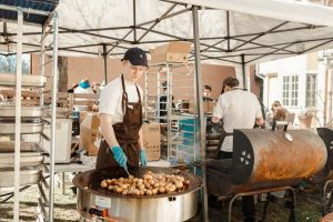 Fredrik Karlsson står utomhus och tillagar massor av potatis.