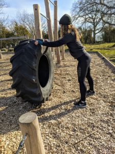 Bild på Julia Dürr där hon gör övningen "Tire flipp" på ett utegym. Detta gör hon genom att lyfta ett stor däck.