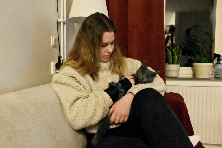 Paula sitter i en soffa med katten Essa i famnen.