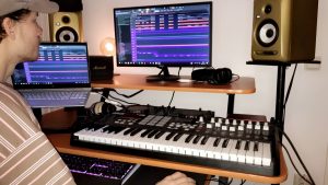 Man ser en kille sitta vid ett keybord och flera skärmar framför sig.