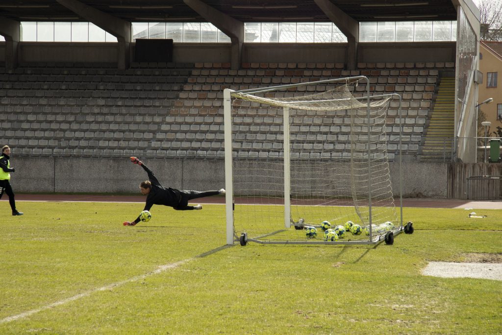 Målvakt som slänger sig efter bollen vid mållområdet.