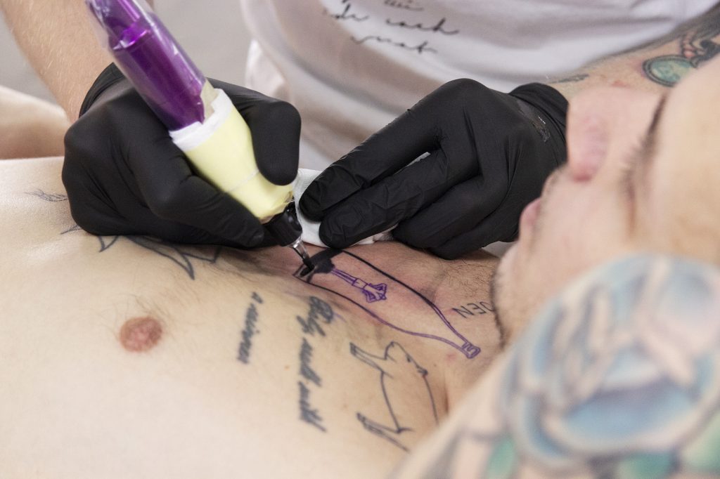 Ola Petersson tatuerar in en gubbe som hoppar studsmatta på sin kunds bröst.