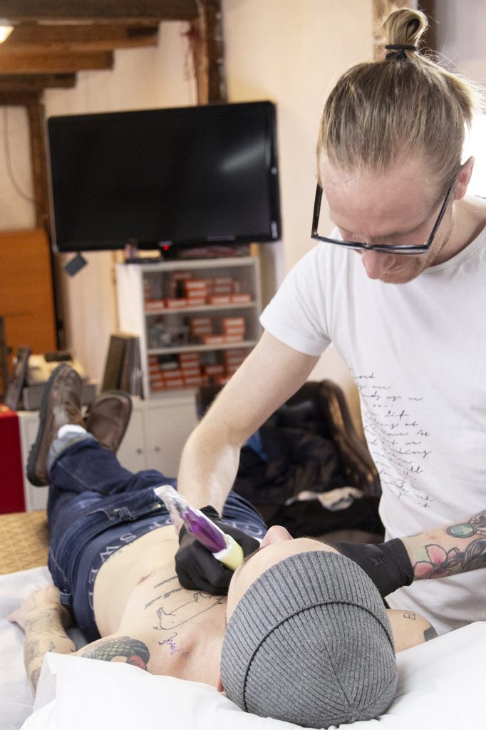 Ola Petersson tatuerar in en gubbe som hoppar studsmatta på sin kunds bröst.