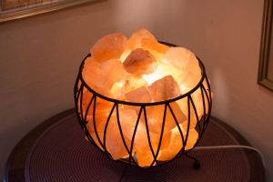 Bild på saltstenar i en svart skål. Det är en lampa under saltstenarna som gör att stenarna lyser.