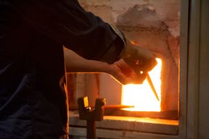 Konstnären Rune Reisænen arbetar vid ugnen, varmt ljussken.