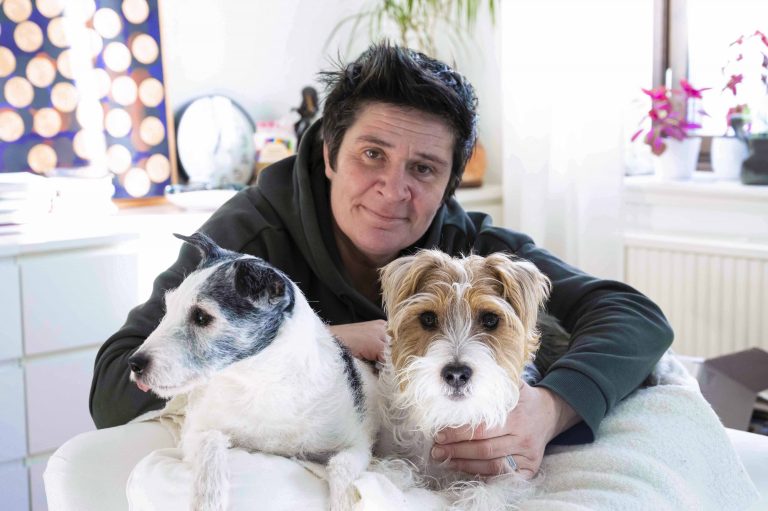 Joanna står bakom sina hundra som ligger på ryggstödets topp av en fåtölj. De tittar in i kameran.