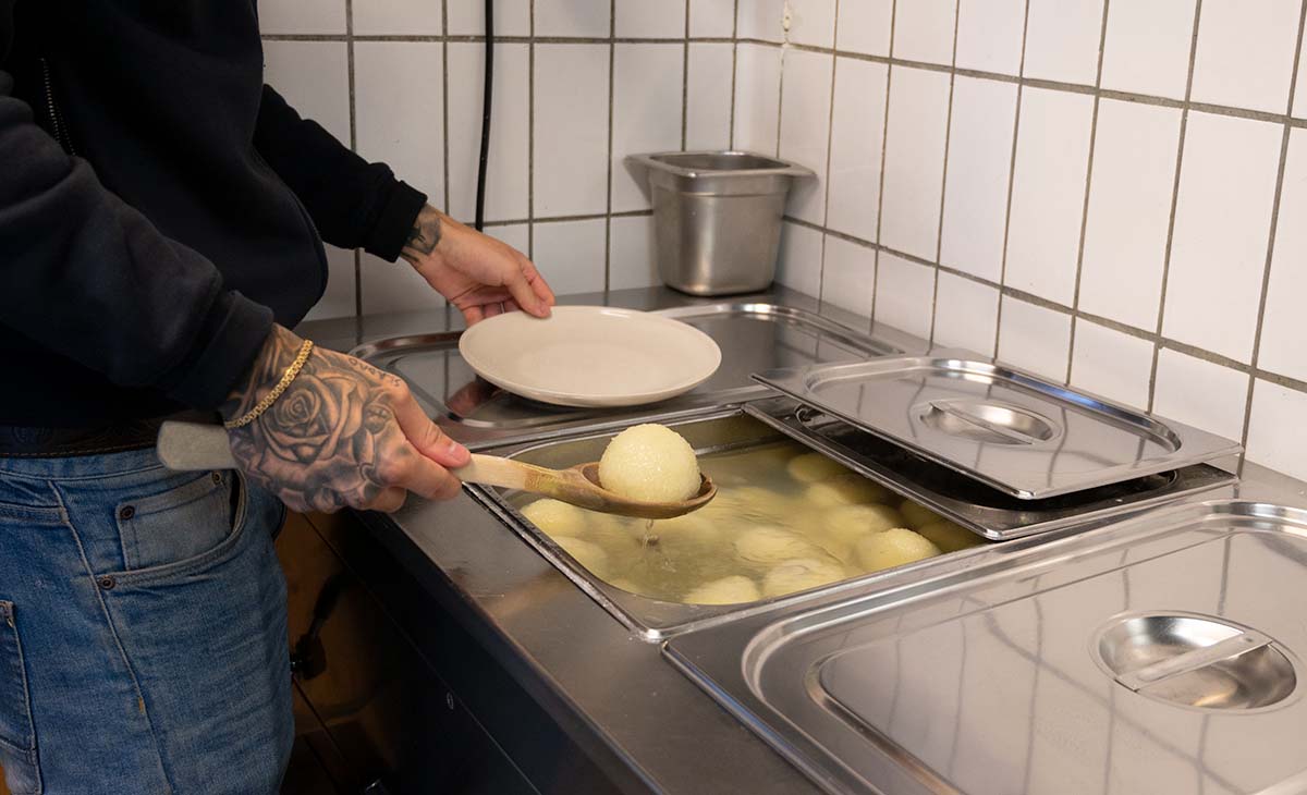 En kroppkaka läggs upp på ett fat.