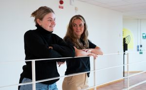 Två tjejer står lutade mot ett räcke.