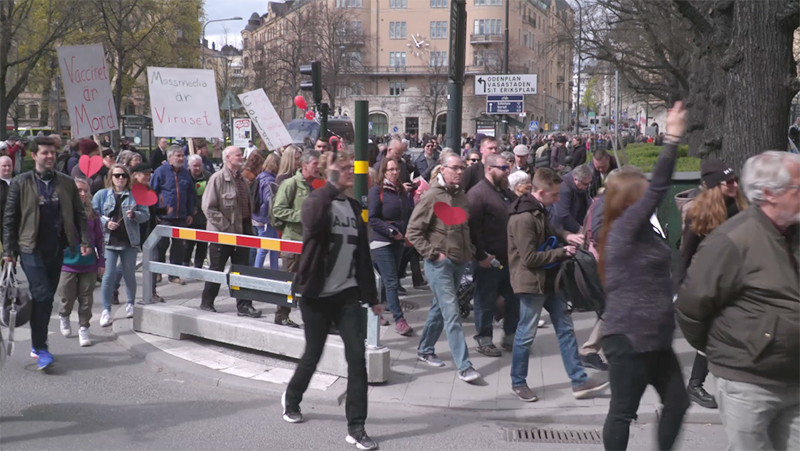 Många människor som går med skyltar i demonstration mot vaccin