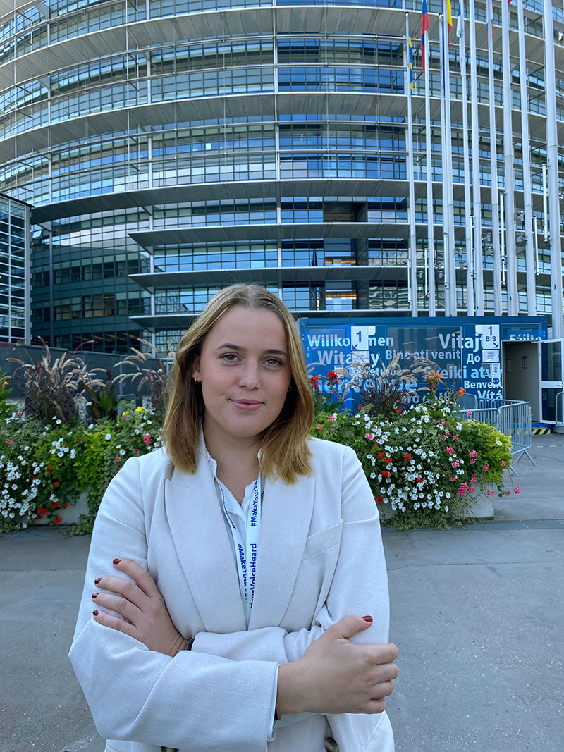 Nellie Jakobsson ståendes framför Europaparlamentets byggnad i Strasbourg