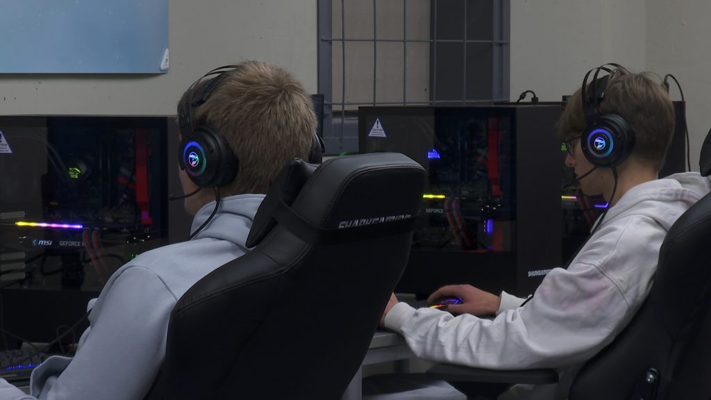 Två gymnasieelever spelar på datorer.