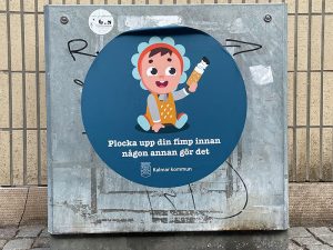 Tecknad bild av en bebis som har plockat upp en cigarettfimp med texten "Plocka upp din fimp innan någon annan gör det".