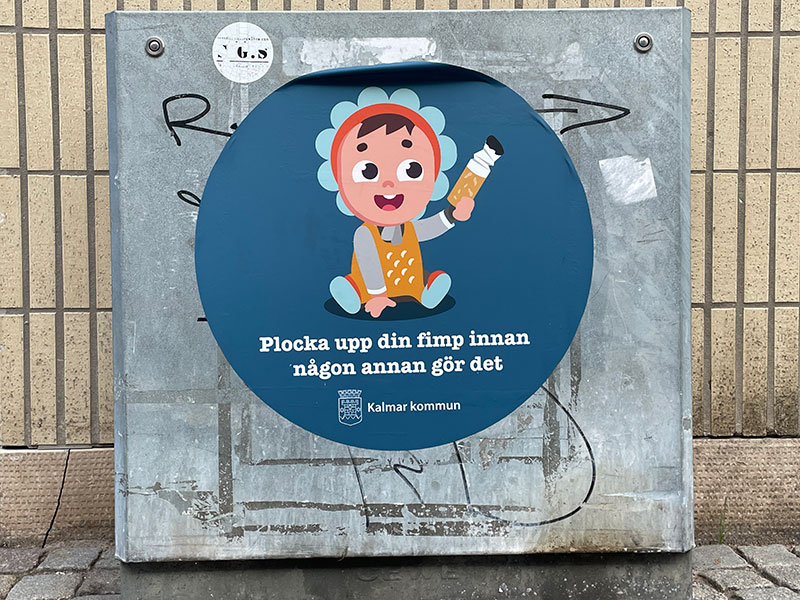 Tecknad bild av en bebis som har plockat upp en cigarettfimp med texten "Plocka upp din fimp innan någon annan gör det".