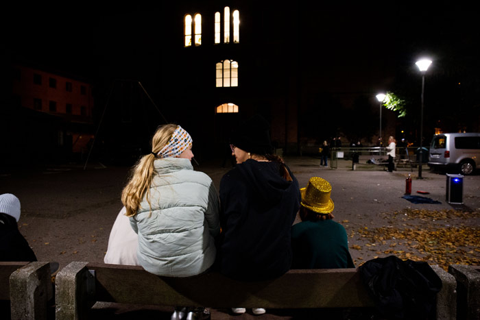 Fyra tjejer sitter på en bänk, med ryggen vänd mot kameran.