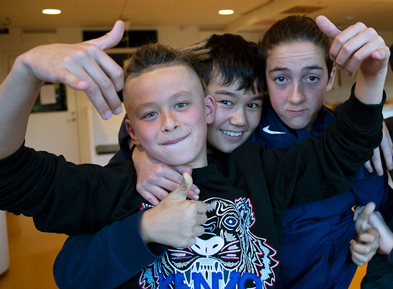 Tre pojkar poserar framför kameran.