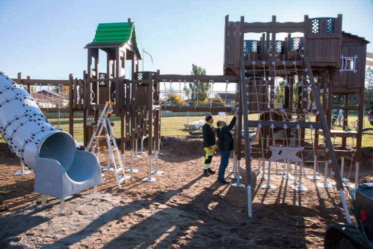 Lekplats i Köpingsvik, Borgholm håller på att byggas. Två personer med arbetarkläder inspekterar den nybyggda klätterställningen.