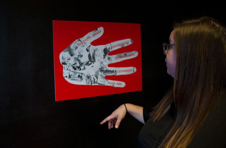 Fritidsledare Frida Toll visar upp ett konstverk föreställande en hand.