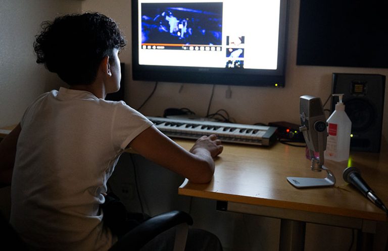 Pojke sitter i ett mörkt rum framför en datorskärm.