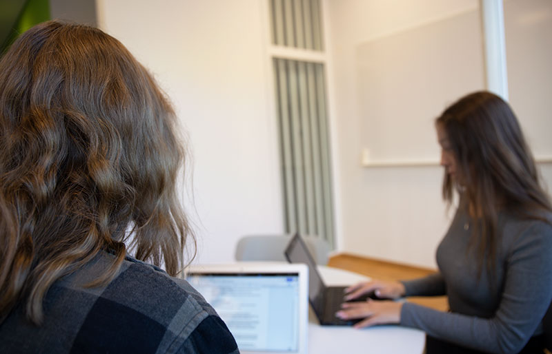 Två kvinnliga studenter sitter framför varsin dator.