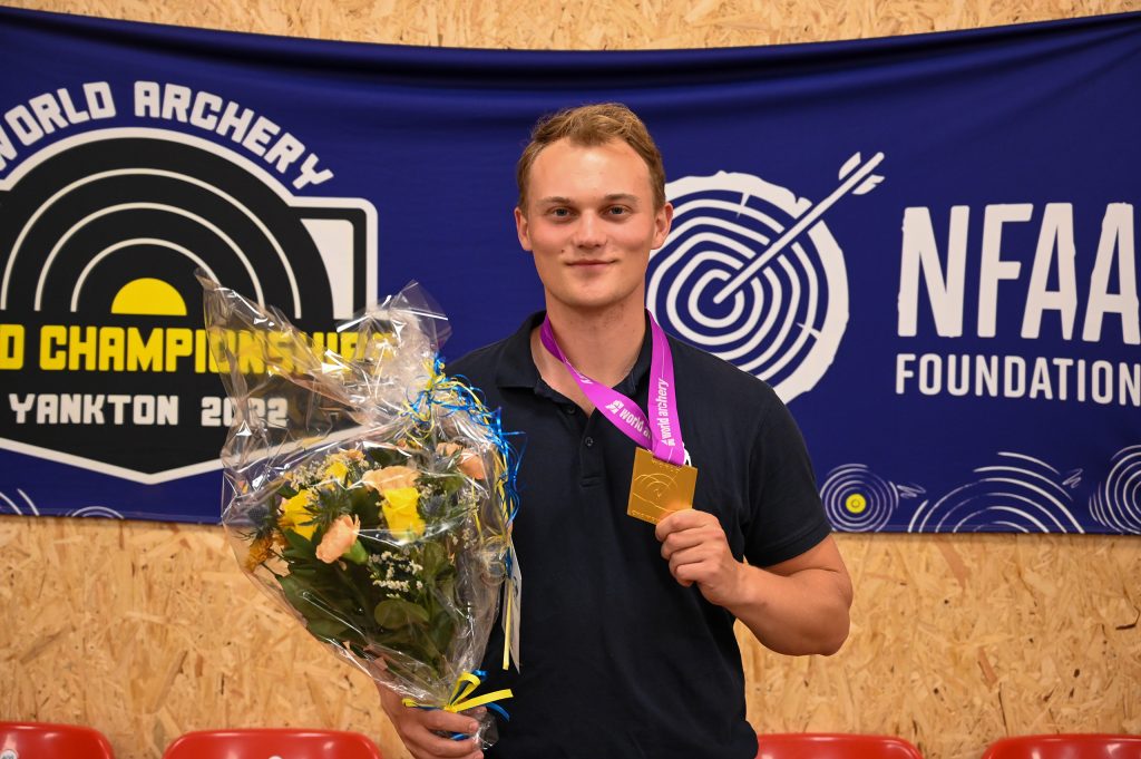 Jacob Benschjöld som håller upp en medalj och en bukett med blommor