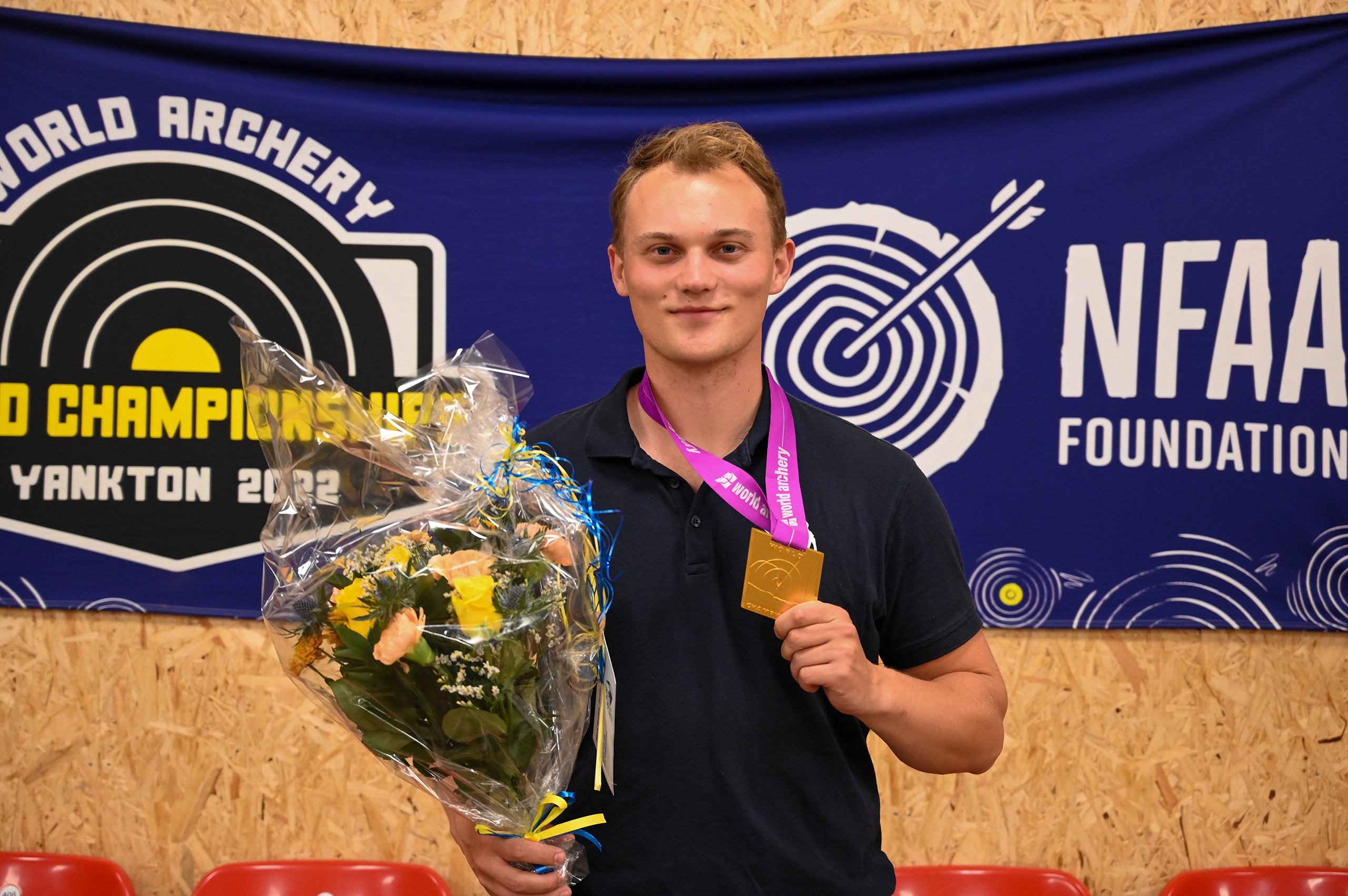 Jacob Benschjöld som håller upp en medalj och en bukett med blommor
