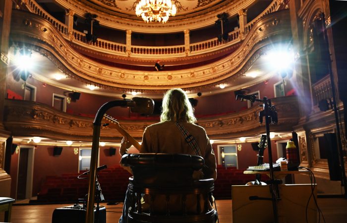 Marcus sitter på scenen och är fotograferad bakifrån.