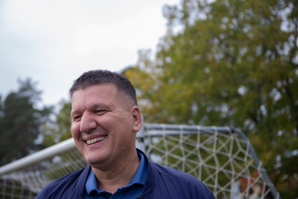 Shemsi "Papi" Brahimi står och ler. I bakgrunden syns hörnet av ett fotbollsmål.