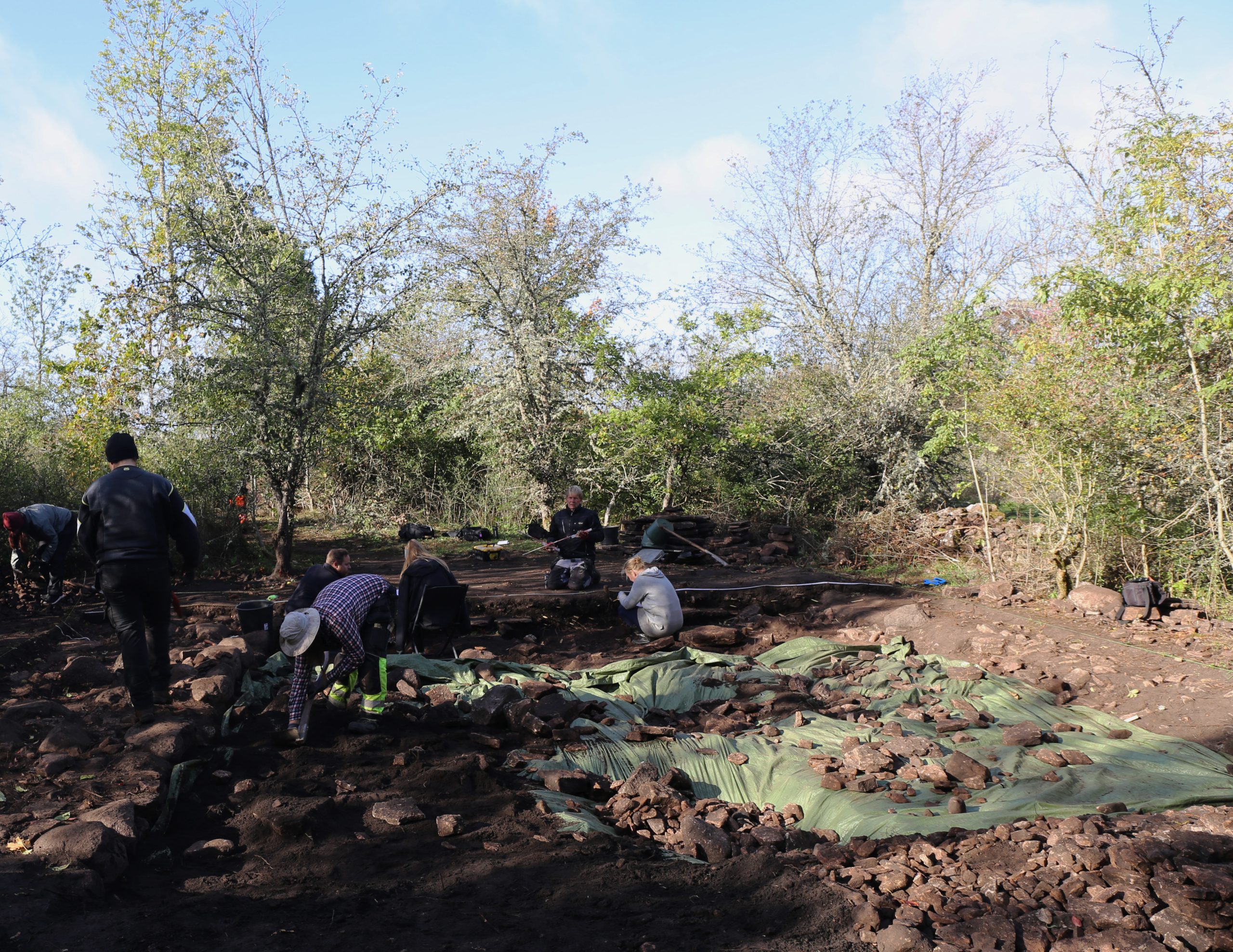 Flera människor gräver och flyttar sten under utgrävningen.