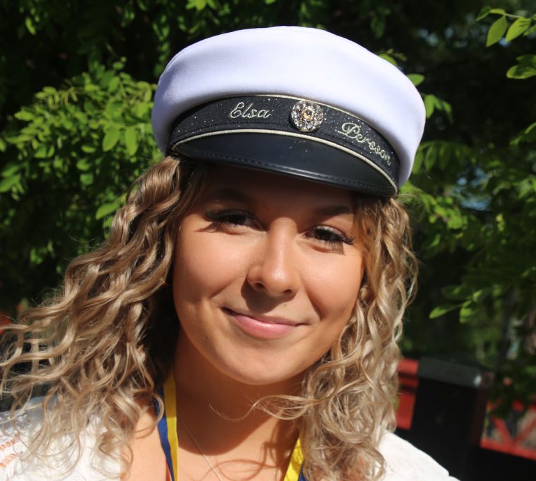 Elsa Persson står och ler mot kameran med sin studentmössa på huvudet.