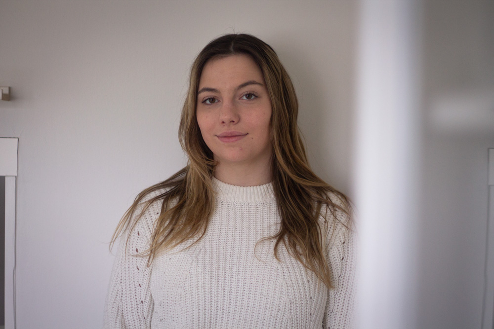 Nhea Nilsson i en vit tröja framför en vit vägg.