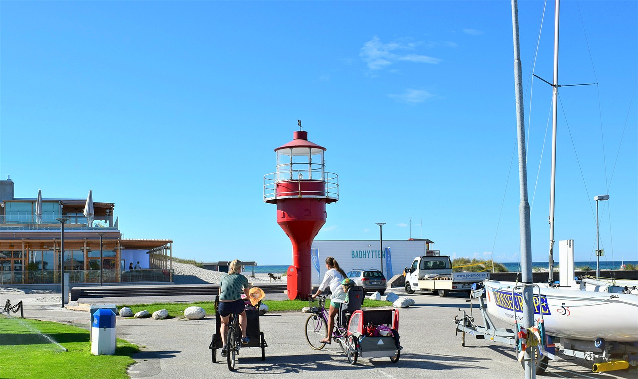 Folk cyklar på Skanör hamn. I bakgrunden syns Skanörs röda fyr.