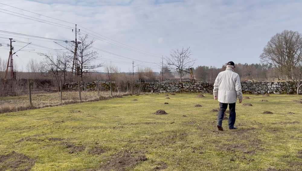 Sten-Åke Nilsson går bort från kameran. Järnvägen syns i bakgrunden.