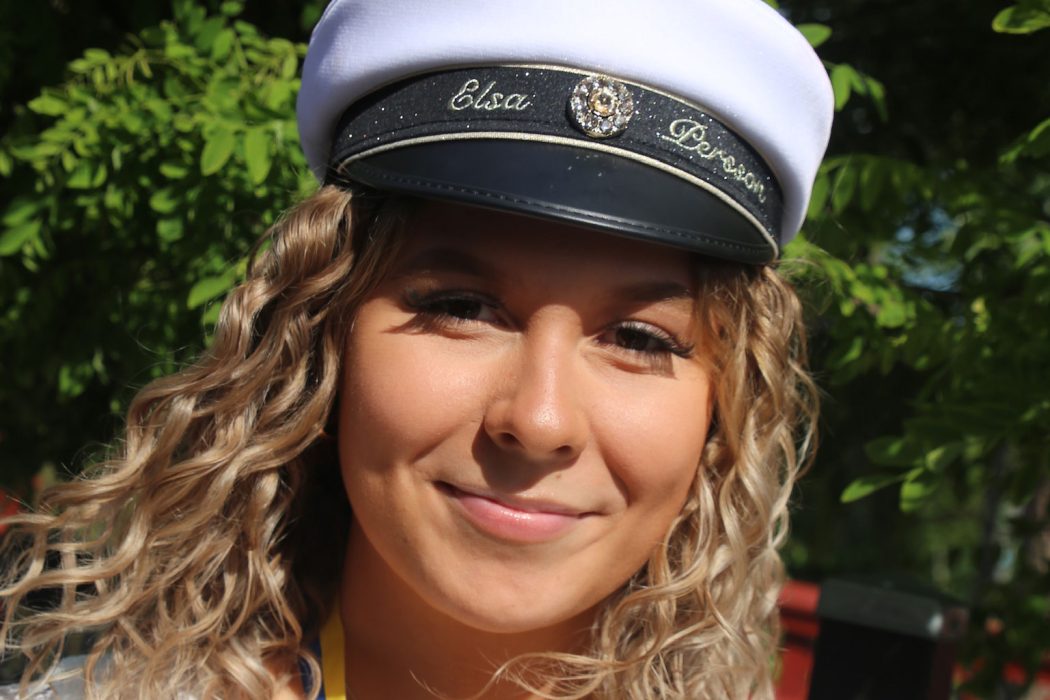 Elsa Persson står och ler mot kameran med sin studentmössa på huvudet.