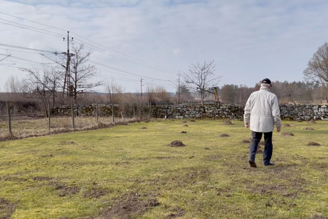 Sten-Åke Nilsson går bort från kameran. Järnvägen syns i bakgrunden.